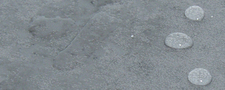 Bodenfliese partiell behandelt mit WAYTONA® Steinbodenversiegelung -nichtsaugend-. Deutlich ist der abstoßende Effekt auf der behandelten rechten Seite zu erkennen.